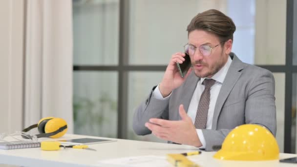 Ingeniero de mediana edad enojado hablando por teléfono mientras usa el ordenador portátil — Vídeo de stock