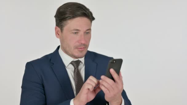 Uomo d'affari di mezza età che festeggia su smartphone, sfondo bianco — Video Stock