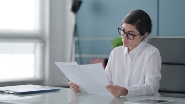 Indiase zakenvrouw die rapporten leest terwijl ze op kantoor zit — Stockvideo