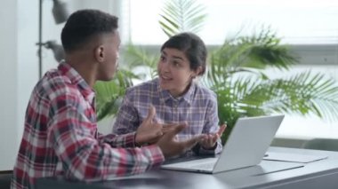 Afrikalı Adam ve Hintli Kadın Laptop üzerinde çalışırken tartışıyor 