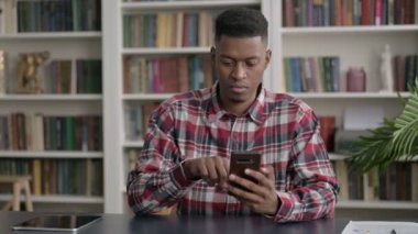 Ofiste akıllı telefon kullanan Afrikalı adam 