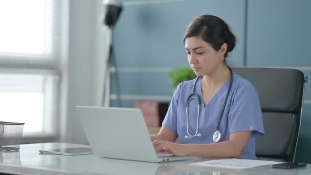 Indiska kvinnliga läkare tittar på kameran när du använder laptop i Office — Stockvideo