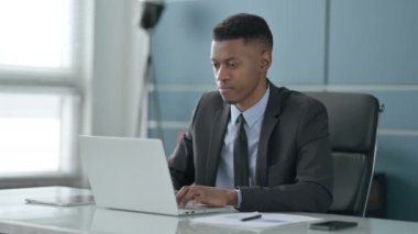 Ofiste dizüstü bilgisayar kullanırken Afrikalı İşadamı Kameraya Bakıyor