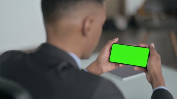 Vista trasera del empresario africano que mira el teléfono inteligente con pantalla de croma — Vídeos de Stock