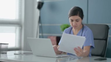 Dizüstü bilgisayarlı Hintli Kadın Doktor Ofiste Belgeler Okuyor 
