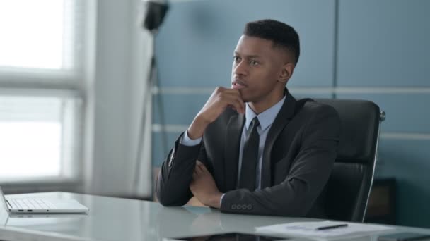 Homme d'affaires africain pensif pensant tout en étant assis dans le bureau — Video