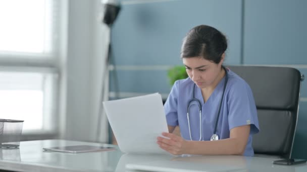 Indiana feminino médico leitura relatórios enquanto sentado no escritório — Vídeo de Stock