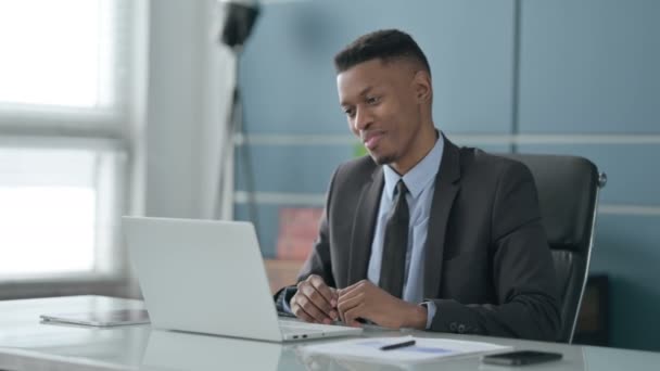 Αφρικανός επιχειρηματίας Μιλώντας σε βίντεο κλήση στο φορητό υπολογιστή στο γραφείο — Αρχείο Βίντεο
