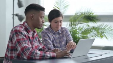 Dizüstü bilgisayarda çalışan Afrikalı Adam ve Hintli Kadın 