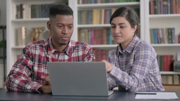 Африканский мужчина и индийская женщина обсуждают работу над ноутбуком — стоковое видео