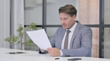 Ofiste Otururken Orta Yaşlı Adam Belgeleri Okuyor