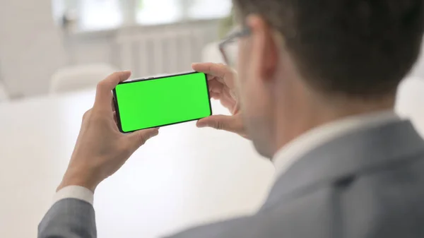 Muž při pohledu na Smartphone se zelenou Chroma obrazovkou — Stock fotografie