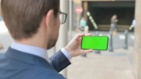 Geschäftsmann schaut auf Smartphone mit grünem Bildschirm — Stockfoto