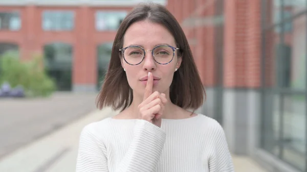 Молода жінка тихо показує пальцем на губах — стокове фото