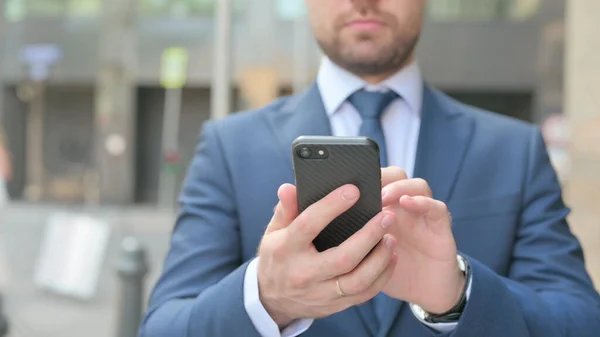 Geschäftsmann bedient Smartphone im Stehen auf der Straße — Stockfoto