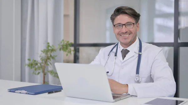 Médico con portátil sonriendo a la cámara en la clínica — Foto de Stock