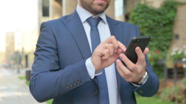 Sokakta yürürken akıllı telefon kullanan genç iş adamının ellerini kapat.