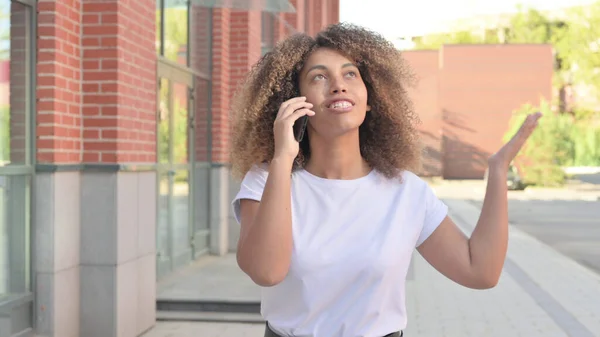Mladá africká žena mluví na telefonu při chůzi venku — Stock fotografie