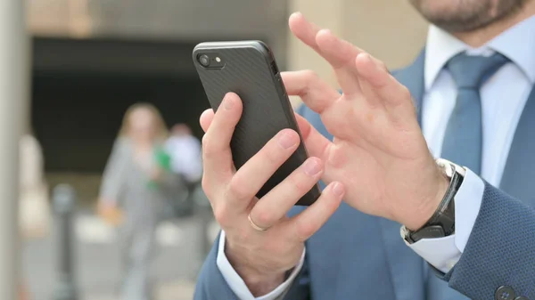 Geschäftsmann benutzt Smartphone, während er auf der Straße steht — Stockfoto