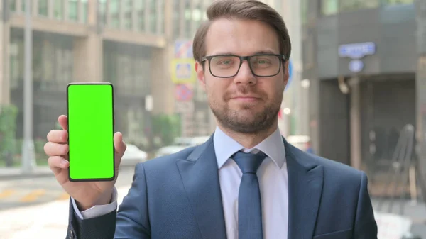 Jeune homme d'affaires tenant Smarthone avec écran chroma vert — Photo