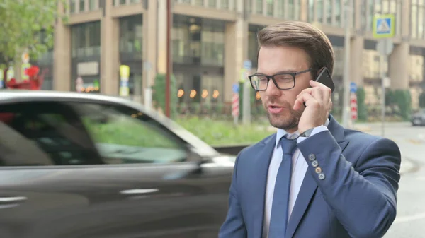 Ung affärsman talar på Smartphone när du går på gatan — Stockfoto