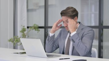 Orta yaşlı adam dizüstü bilgisayarda çalışırken hayal kırıklığına uğruyor