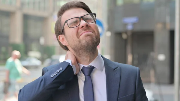 Fiatal üzletember, akinek nyaki fájdalma van, miközben a szabadban áll — Stock Fotó