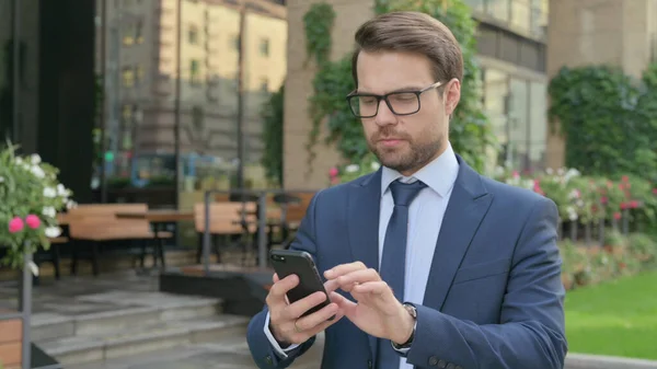 Junger Geschäftsmann benutzt Smartphone, während er in Zeitlupe auf der Straße läuft — Stockfoto