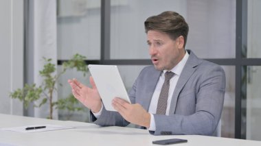 Orta Yaşlı Adam Ofiste Otururken Tabletteki Kayıplara Tepki Veriyor