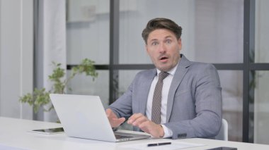 Ofiste dizüstü bilgisayar kullanırken Orta Yaşlı Adam Şok Oldu