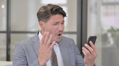 Orta yaşlı adam akıllı telefon kullanırken kayboluyor.