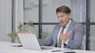 Ofiste dizüstü bilgisayar kullanırken Orta Yaşlı Adam Kayıplara Tepki Veriyor