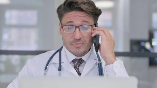Primer plano del médico con el ordenador portátil hablando por teléfono — Foto de Stock