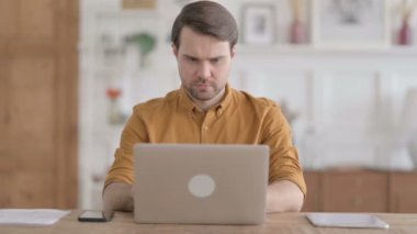 Ofiste dizüstü bilgisayarda çalışan genç adam.