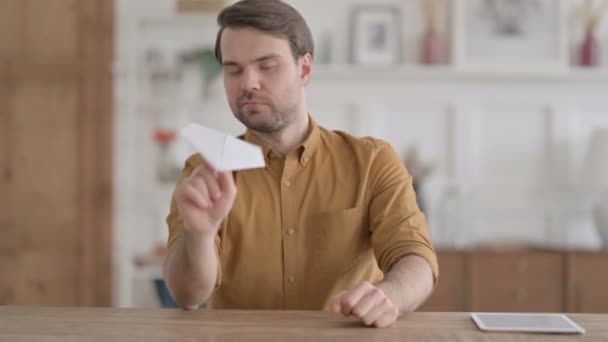 オフィスに座りながら紙飛行機を作る青年 — ストック動画