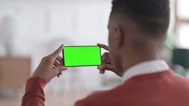 Achteraanzicht van Afrikaanse Man Kijkend naar Smartphone met Green Screen — Stockvideo