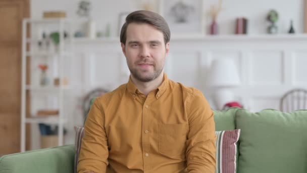 Porträtt av ung man visar tummen upp hemma — Stockvideo