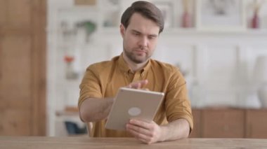 Ofiste otururken Tablet kullanan genç adam