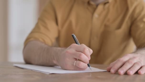 Hände in Großaufnahme von jungem Mann, der auf Papier schreibt — Stockvideo