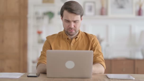Νεαρός με φορητό υπολογιστή που έχει πόνο στο λαιμό στον καναπέ — Αρχείο Βίντεο