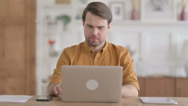 Молодой человек реагирует на потерю во время использования ноутбука — стоковое видео