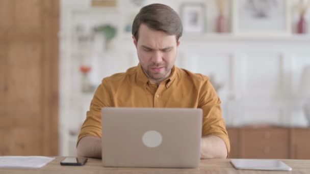 Молодой человек кашляет во время использования ноутбука в офисе — стоковое видео