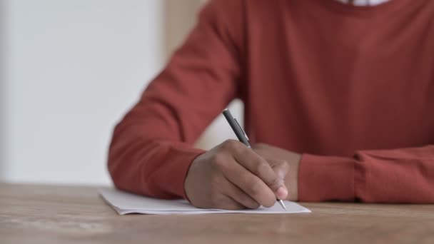 Handen close-up van de Afrikaanse man schrijven op papier — Stockvideo