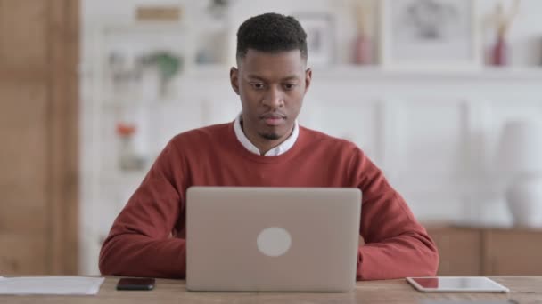 Африканський чоловік кашляє, користуючись ноутбуком у офісі — стокове відео