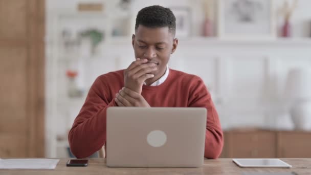 Африканський чоловік, який задирався, користуючись ноутбуком у офісі — стокове відео