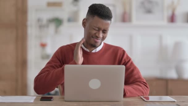 African Man mając ból szyi podczas korzystania z laptopa w biurze — Wideo stockowe