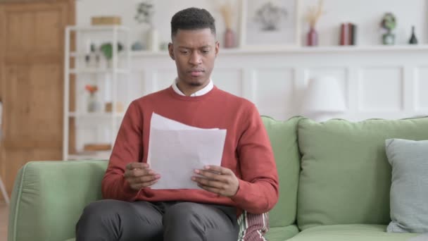 Uomo africano che reagisce alla perdita su documenti, divano — Video Stock