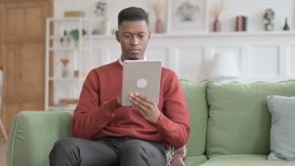 African Man använder Tablet på soffan — Stockvideo