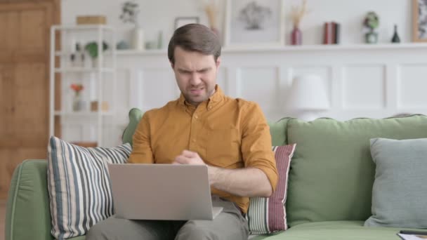 Giovane con computer portatile con dolore al polso sul divano — Video Stock