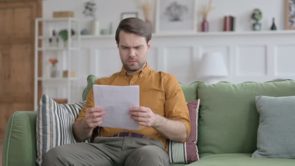 Giovane uomo che reagisce alla perdita su documenti, divano — Video Stock